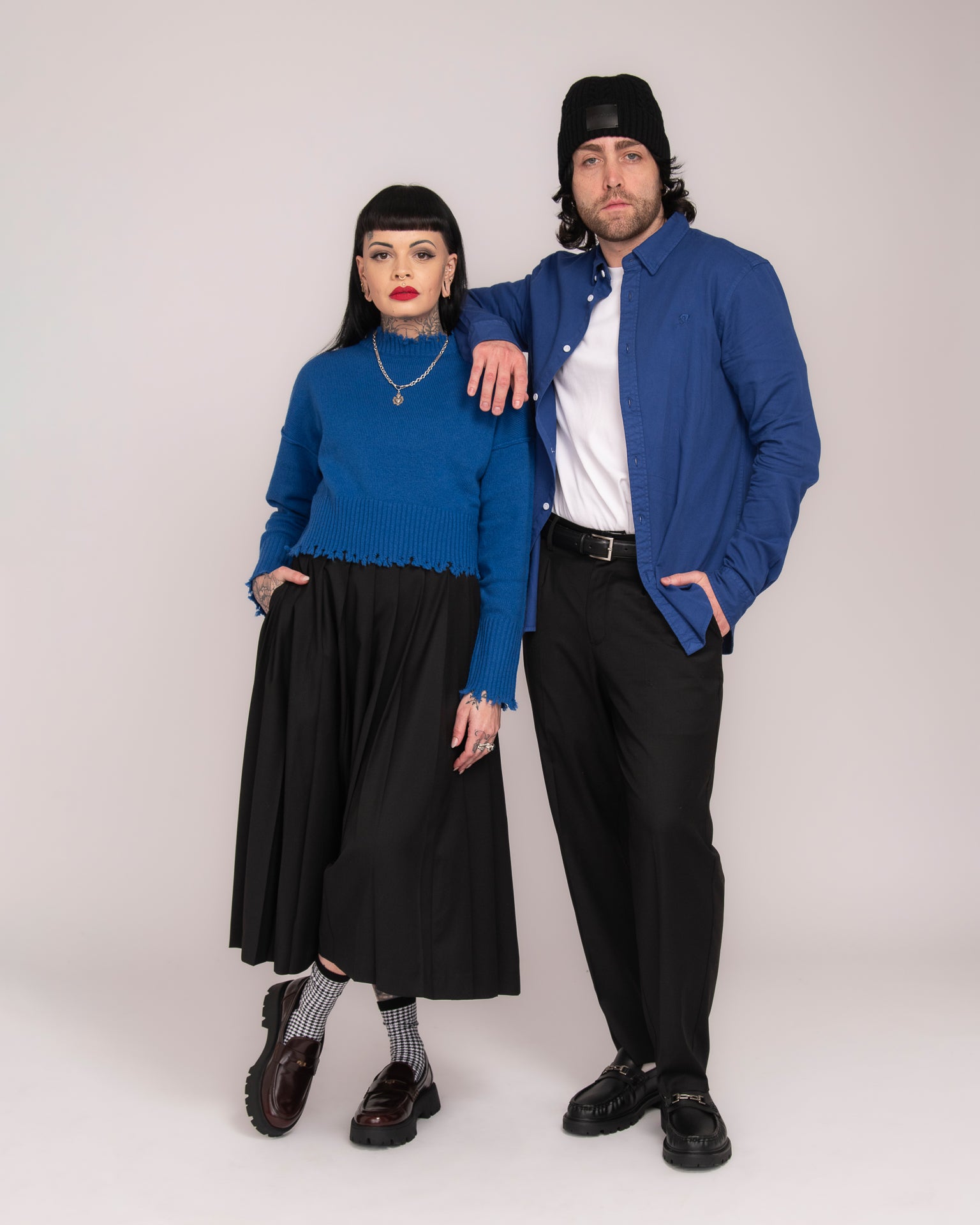 Two people wearing matching blue jackets on a plain background